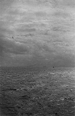 Picture taken from transport off Kwajalein Atoll. Atoll barely visible on horizon. A heavy barrage hit the atoll before troops were sent in.Smoke can be seen rising in center-left of picture. Picture, George Smith.