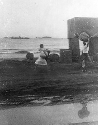 Two Phillipine natives. One carries bundle on head. Picture also shows beach which is about 25yds.from where we lived.